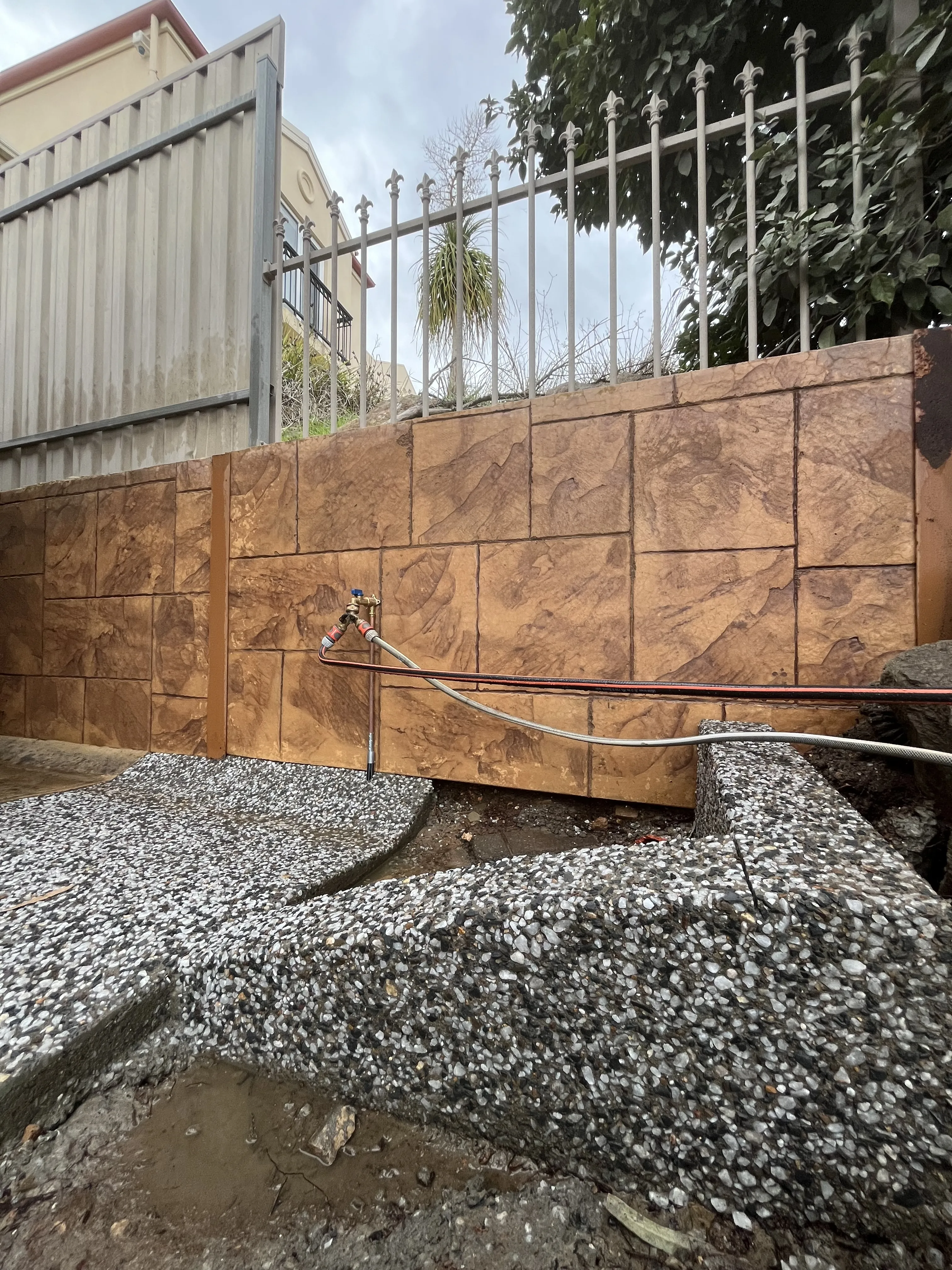 Exposed aggregate concrete underneath a water tap